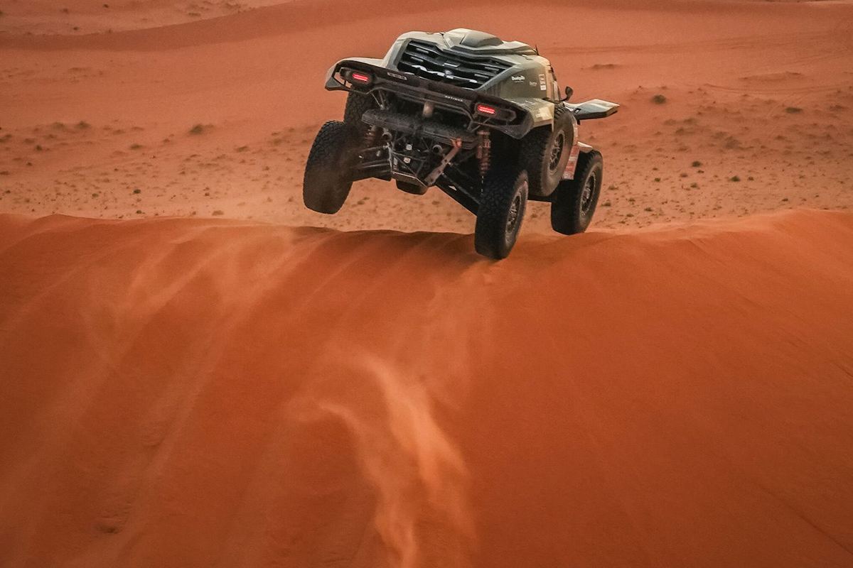 UTV en el aire sobre una duna de arena.
